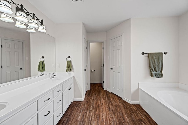 bathroom with hardwood / wood-style flooring, vanity, and a bath