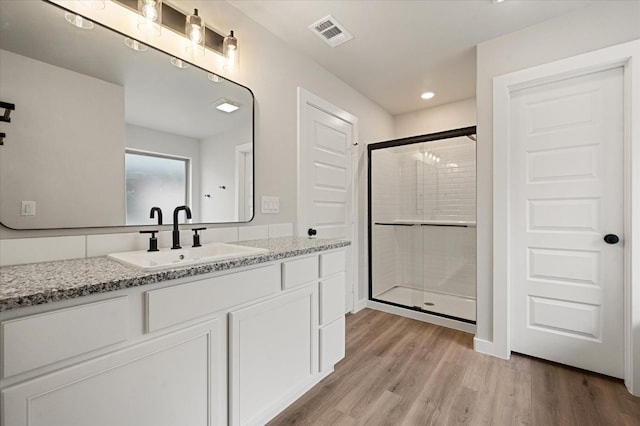 bathroom featuring wood-type flooring, vanity, and walk in shower