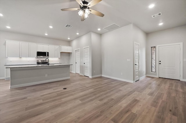 kitchen featuring sink, white cabinets, ceiling fan, a center island with sink, and light wood-type flooring