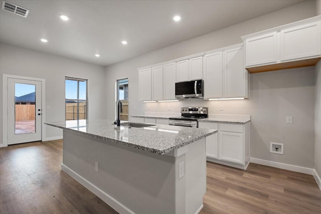 kitchen with stainless steel appliances, sink, a center island with sink, and white cabinets