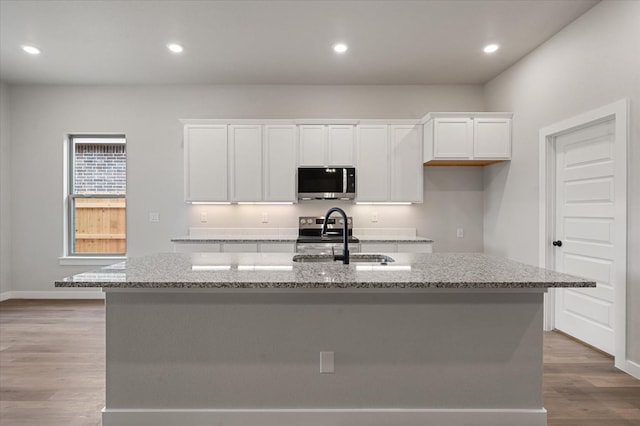 kitchen with sink, an island with sink, white cabinets, and appliances with stainless steel finishes