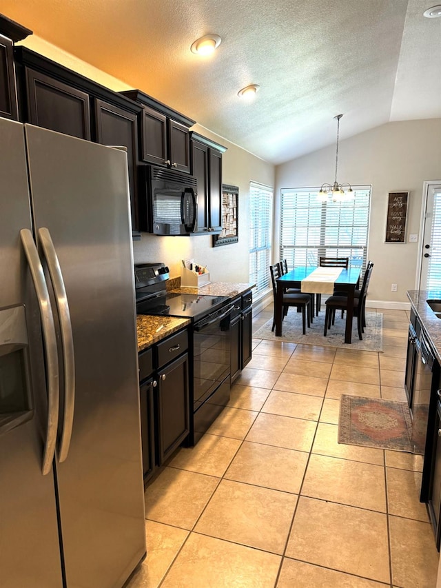 kitchen with light tile patterned floors, light stone counters, black appliances, decorative light fixtures, and vaulted ceiling