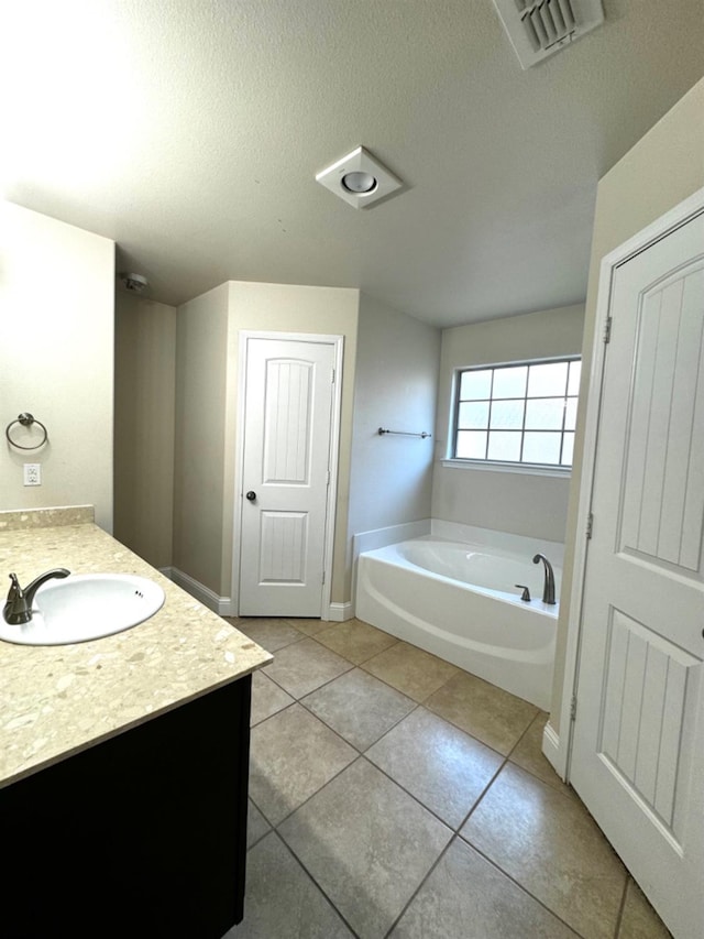 bathroom with vanity, a bathtub, tile patterned floors, and a textured ceiling