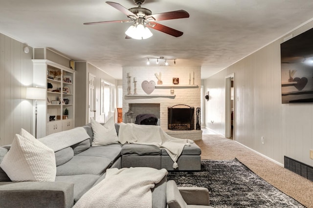 living room featuring ceiling fan, carpet floors, a brick fireplace, and wood walls