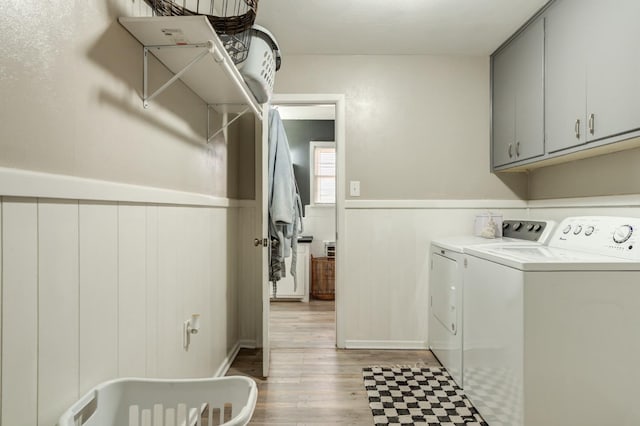 laundry room featuring independent washer and dryer, cabinets, and light hardwood / wood-style floors