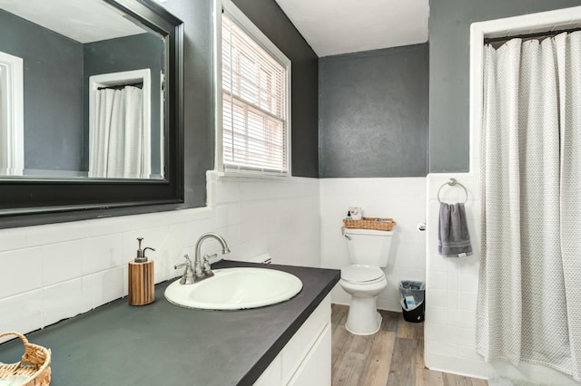 bathroom with walk in shower, toilet, tile walls, vanity, and hardwood / wood-style flooring