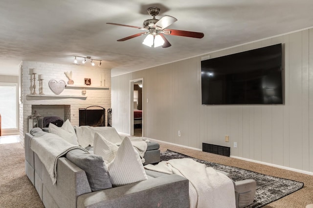 carpeted living room featuring ceiling fan, wooden walls, and a fireplace