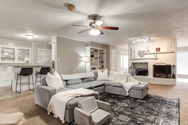 carpeted living room with ceiling fan and a brick fireplace