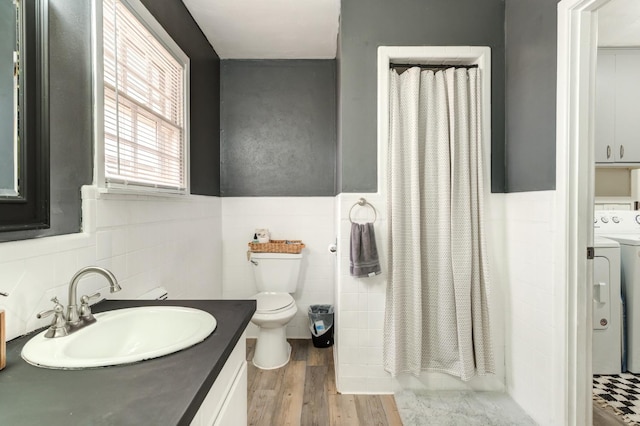 bathroom featuring toilet, washer / dryer, wood-type flooring, tile walls, and vanity