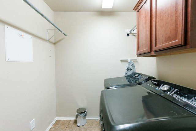 washroom with cabinets, light tile patterned floors, and washing machine and clothes dryer