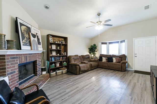 living room featuring ceiling fan, lofted ceiling, a fireplace, and light hardwood / wood-style floors