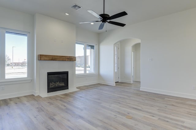 11806 Kenosha Ave, Lubbock, TX 79423 - unfurnished living room featuring a glass covered fireplace, light wood finished floors, arched walkways, a ceiling fan, and recessed lighting