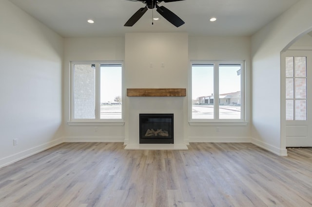 11806 Kenosha Ave, Lubbock, TX 79423 - unfurnished living room with a glass covered fireplace, plenty of natural light, arched walkways, wood finished floors, and recessed lighting