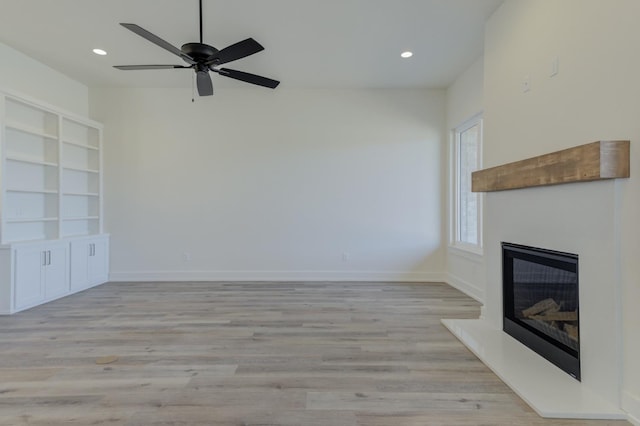 11806 Kenosha Ave, Lubbock, TX 79423 - unfurnished living room featuring a glass covered fireplace, light wood-type flooring, recessed lighting, built in shelves, and a ceiling fan