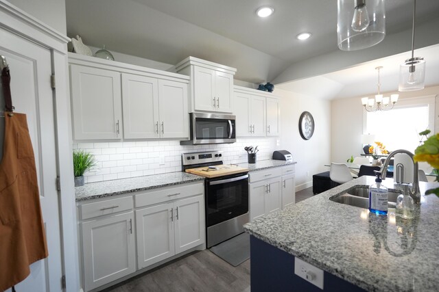 7813 89th St, Lubbock, TX 79424 - kitchen featuring light stone counters, appliances with stainless steel finishes, a sink, dark wood finished floors, and decorative backsplash