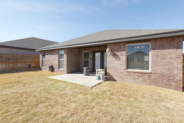 7813 89th St, Lubbock, TX 79424 - back of house featuring fence, a shingled roof, brick siding, a patio area, and a lawn