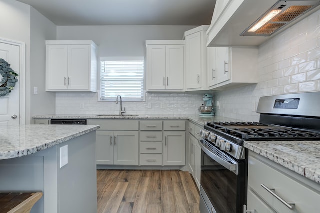 kitchen featuring a sink, stainless steel gas stove, light stone countertops, exhaust hood, and wood finished floors