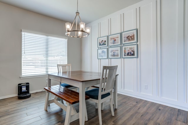 dining room with a decorative wall, a notable chandelier, wood finished floors, and baseboards