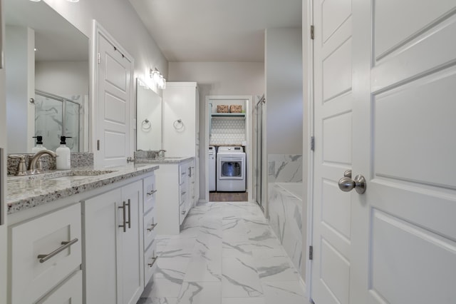bathroom featuring vanity, a marble finish shower, marble finish floor, and washing machine and dryer