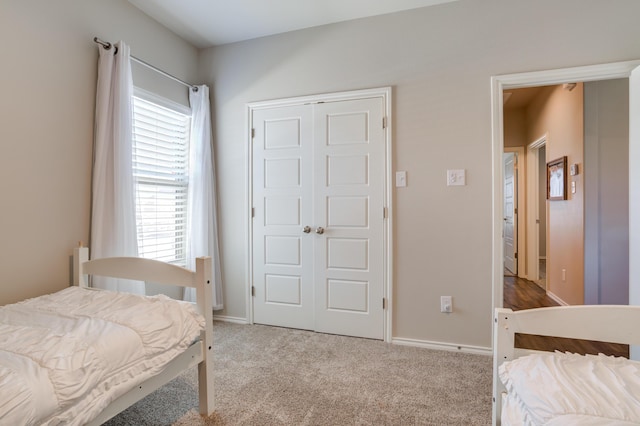 carpeted bedroom featuring a closet, multiple windows, and baseboards