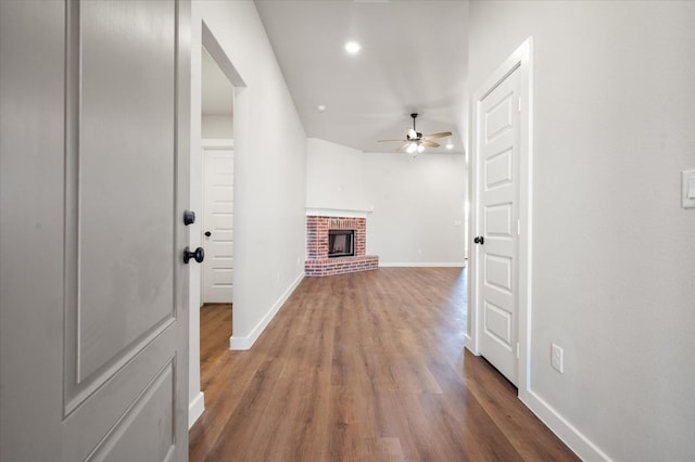 living room with hardwood / wood-style flooring, ceiling fan, and a brick fireplace