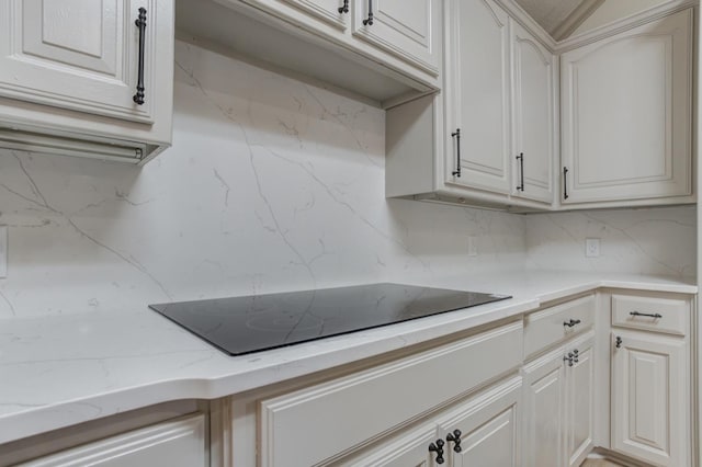 kitchen featuring white cabinetry, black electric stovetop, and tasteful backsplash