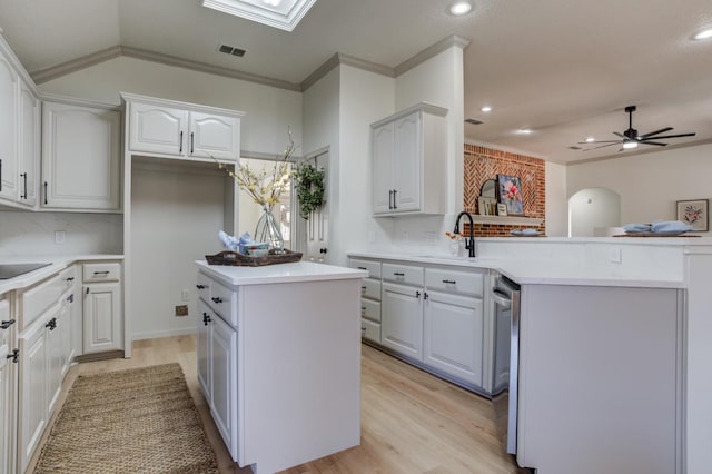 kitchen with a kitchen island, white cabinetry, sink, kitchen peninsula, and light wood-type flooring