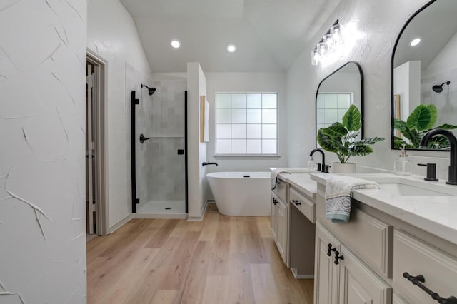 bathroom with independent shower and bath, vanity, lofted ceiling, and hardwood / wood-style flooring