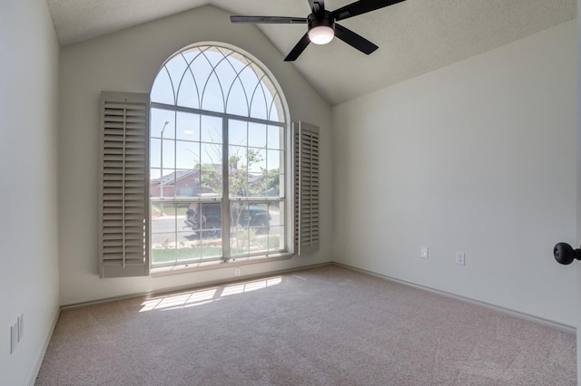 carpeted spare room featuring vaulted ceiling, a textured ceiling, and ceiling fan