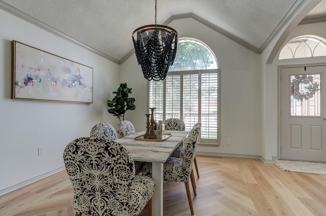 dining space featuring vaulted ceiling, ornamental molding, a notable chandelier, a healthy amount of sunlight, and a textured ceiling