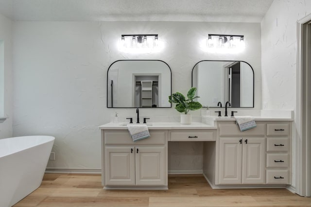 bathroom featuring hardwood / wood-style flooring, vanity, a tub, and a textured ceiling