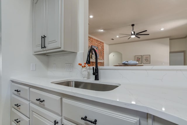 kitchen with ceiling fan, sink, white cabinets, and light stone counters