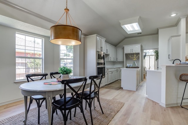 dining space with crown molding, plenty of natural light, and light hardwood / wood-style flooring