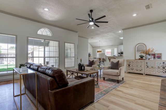 living room featuring crown molding, ceiling fan, light hardwood / wood-style flooring, and a textured ceiling