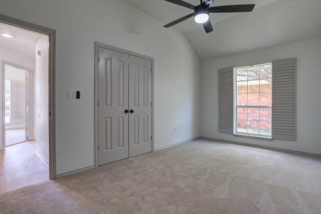 unfurnished bedroom with light carpet, vaulted ceiling, a closet, and ceiling fan