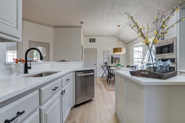 kitchen featuring a wealth of natural light, sink, white cabinets, hanging light fixtures, and stainless steel appliances