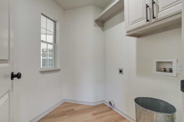 laundry room with electric dryer hookup, hookup for a washing machine, light hardwood / wood-style flooring, and cabinets