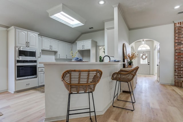 kitchen featuring white cabinetry, crown molding, stainless steel appliances, and a kitchen bar