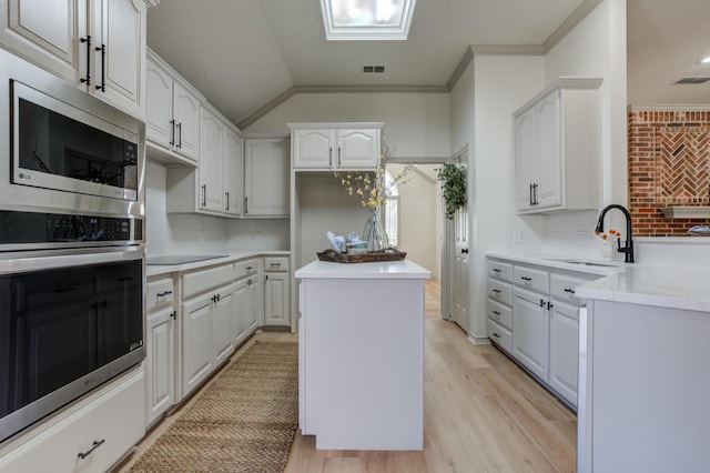 kitchen with sink, a kitchen island, white cabinets, and appliances with stainless steel finishes