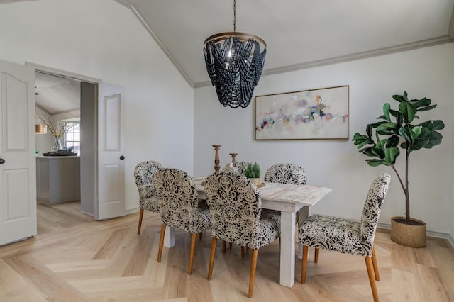 dining area with an inviting chandelier, ornamental molding, light parquet flooring, and lofted ceiling