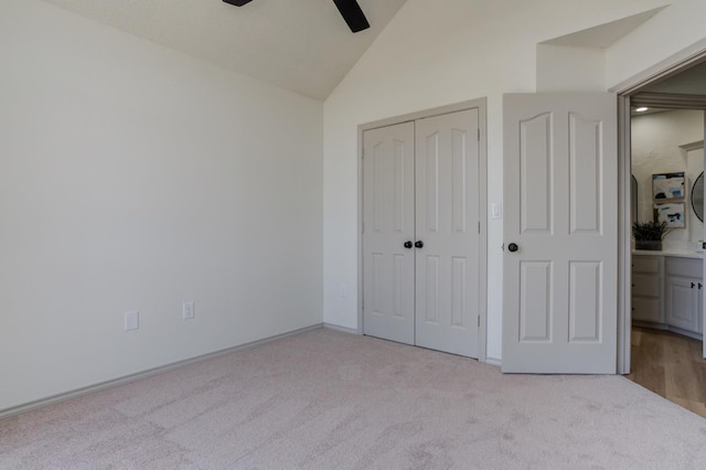 unfurnished bedroom featuring lofted ceiling, light colored carpet, a closet, and ceiling fan