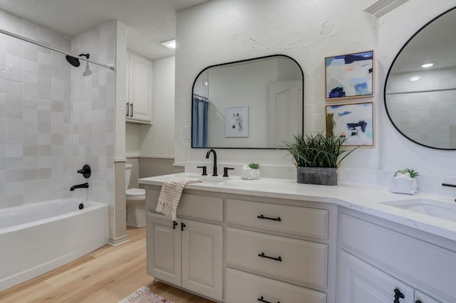 full bathroom featuring hardwood / wood-style flooring, tiled shower / bath, vanity, and toilet