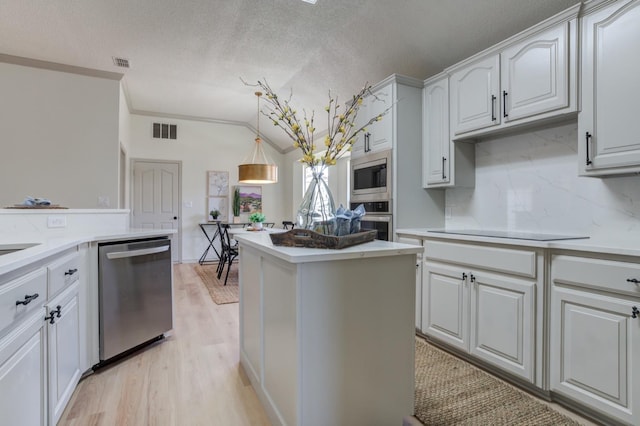 kitchen featuring white cabinetry, hanging light fixtures, stainless steel appliances, light hardwood / wood-style floors, and backsplash