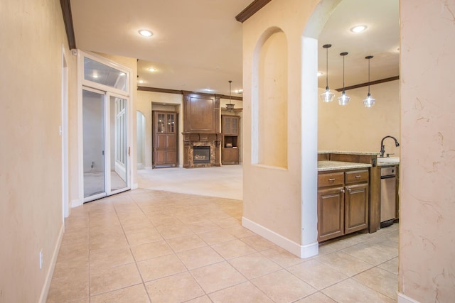 hallway with light tile patterned flooring, arched walkways, a sink, and baseboards