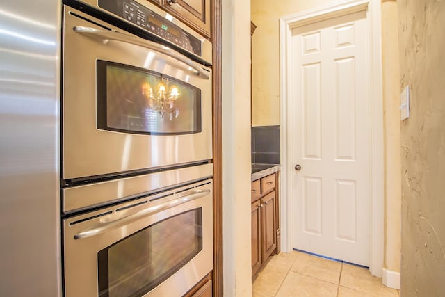 kitchen featuring light tile patterned floors, brown cabinetry, and stainless steel appliances