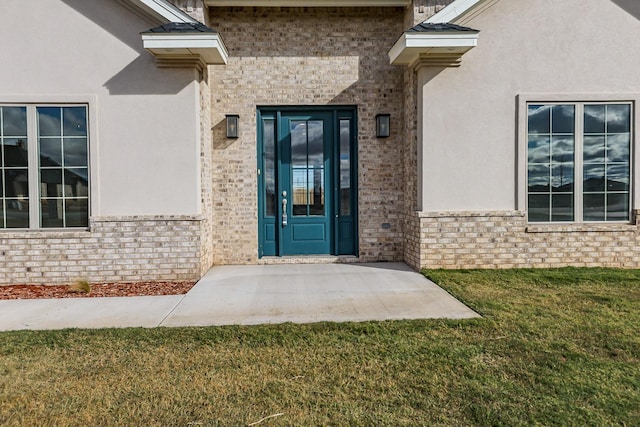 property entrance with a yard, brick siding, and stucco siding