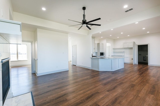 kitchen featuring dark wood-type flooring, ceiling fan, light stone countertops, and white cabinets