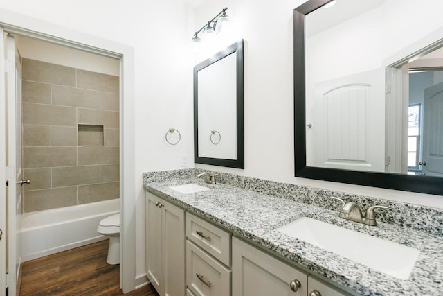 full bath featuring a sink, toilet, wood finished floors, and double vanity