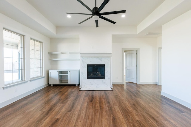 unfurnished living room featuring dark wood-type flooring, a ceiling fan, a high end fireplace, recessed lighting, and baseboards