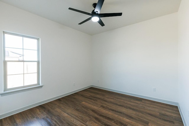 spare room featuring baseboards, ceiling fan, and dark wood-style flooring